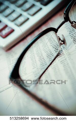 Eyeglasses and a calculator on a financial newspaper View Large Photo Image Picture - Eyeglasses and a calculator on a financial newspaper. Fotosearch