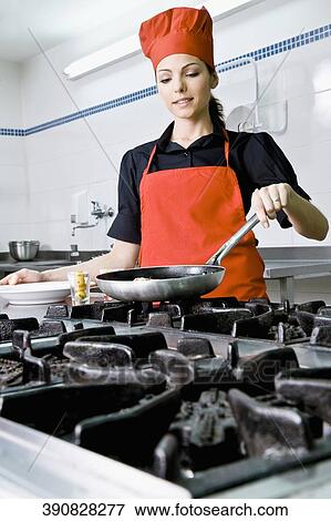 Stock Photo - Female chef cooking food in the kitchen. Fotosearch