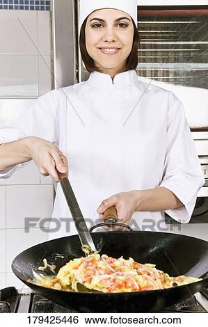 Stock Photograph - Female chef cooking food in the kitchen. Fotosearch