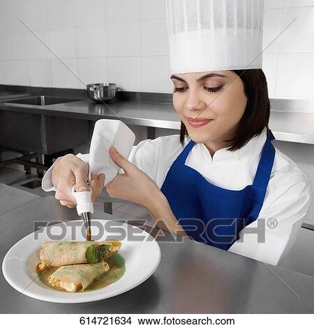 Picture - Female chef decorating pastries and smiling. Fotosearch