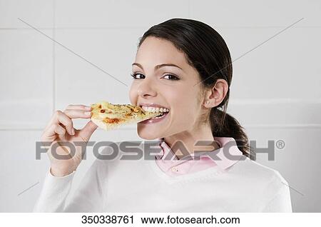 Stock Image - Female chef eating a slice of pizza. Fotosearch