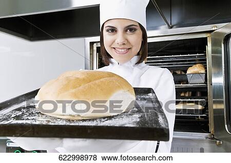 Female chef holding a bun in a tray View Large Photo Image Stock Photo - Female chef holding a bun in a tray. Fotosearch