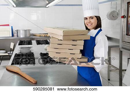 Stock Image - Female chef holding stack of pizza boxes and smiling. Fotosearch