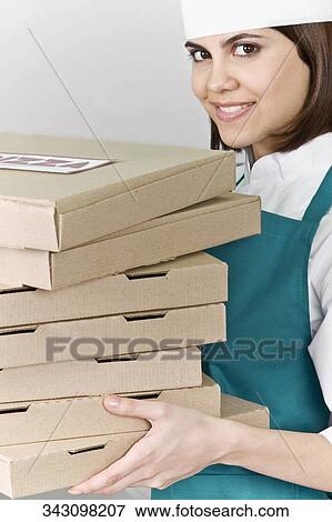 Stock Photo - Female chef holding stack of pizza boxes and smiling. Fotosearch