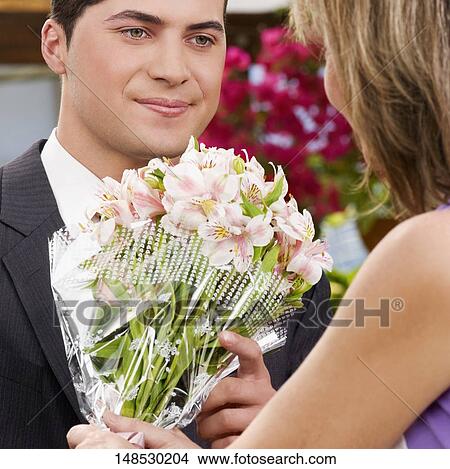 Female florist giving a bouquet of flowers to a customer View Large Photo Image Picture - Female florist giving a bouquet of flowers to a customer. Fotosearch