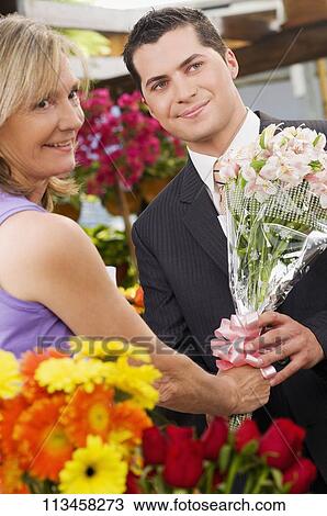 Female florist giving a bouquet of flowers to a customer View Large Photo Image Stock Image - Female florist giving a bouquet of flowers to a customer. Fotosearch
