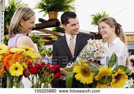 Stock Image - Female florist giving a bouquet of flowers to a woman. Fotosearch