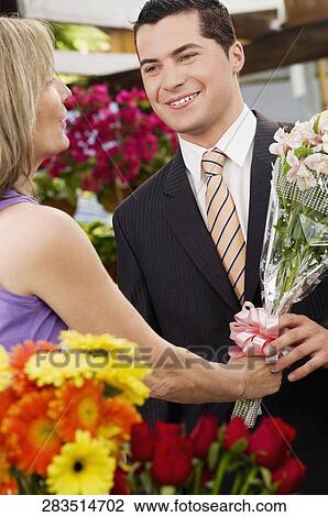 Female florist giving a bouquet of flowers to a customer View Large Photo Image Stock Image - Female florist giving a bouquet of flowers to a customer. Fotosearch