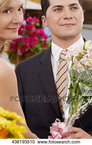 Female florist giving a bouquet of flowers to a customer View Large Photo Image Stock Image - Female florist giving a bouquet of flowers to a customer. Fotosearch