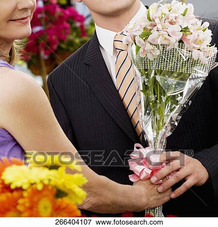 Female florist giving a bouquet of flowers to a customer View Large Photo Image Stock Photo - Female florist giving a bouquet of flowers to a customer. Fotosearch