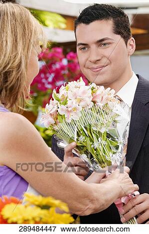 Female florist giving a bouquet of flowers to a customer View Large Photo Image Stock Photo - Female florist giving a bouquet of flowers to a customer. Fotosearch