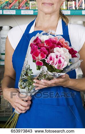 Female florist holding a bouquet of flowers in a flower shop View Large Photo Image Stock Image - Female florist holding a bouquet of flowers in a flower shop. Fotosearch