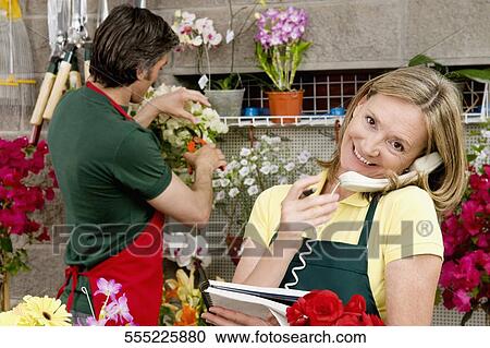 Stock Image - Female florist talking on the phone. Fotosearch