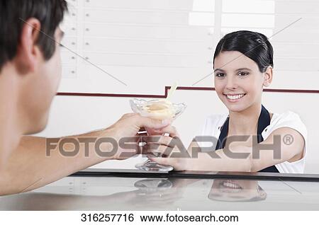 Female ice cream seller giving ice cream to a customer View Large Photo Image Stock Photograph - Female ice cream seller giving ice cream to a customer. Fotosearch