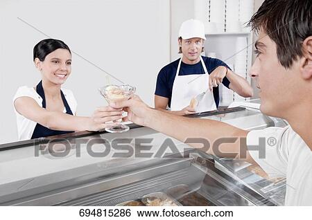 Female ice cream seller giving ice cream to a customer View Large Photo Image Stock Photograph - Female ice cream seller giving ice cream to a customer. Fotosearch