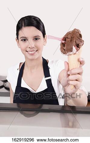 Stock Photograph - Female ice cream seller holding an ice cream cone. Fotosearch