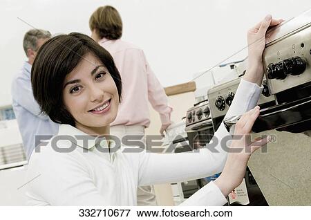 Stock Photo - Female sales clerk showing a gas range. Fotosearch