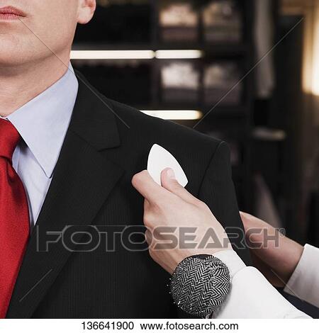 Stock Image - Female tailor taking measurement of a businessman. Fotosearch