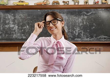 Female teacher adjusting her eyeglasses and smiling View Large Photo Image Stock Photo - Female teacher adjusting her eyeglasses and smiling. Fotosearch