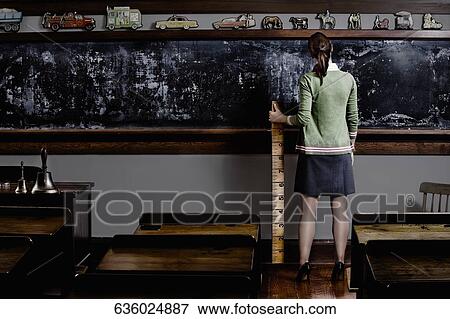 Stock Photo - Female teacher holding a ruler in a classroom. Fotosearch