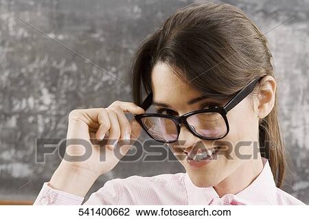 Female teacher looking over her eyeglasses and smiling View Large Photo Image Stock Image - Female teacher looking over her eyeglasses and smiling. Fotosearch