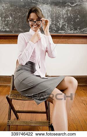 Female teacher sitting on a chair and smiling View Large Photo Image Stock Image - Female teacher sitting on a chair and smiling. Fotosearch