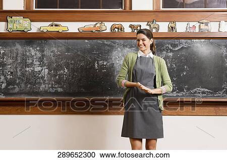Female teacher smiling in in front of a blackboard View Large Photo Image Stock Image - Female teacher smiling in in front of a blackboard. Fotosearch