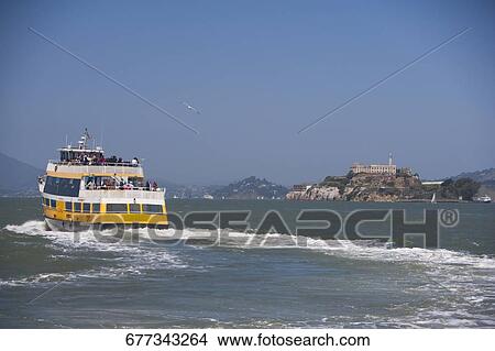 Picture - Ferry in the sea with a prison in the background, Alcatraz Prison, Alcatraz Island, San Francisco Bay, San Francisco, California, USA. Fotosearch