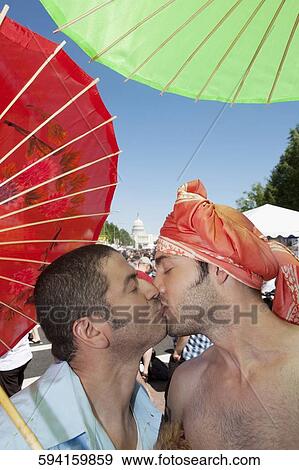 Stock Photo - Gay couple holding parasols and kissing each other, DuPont Circle, Washington DC, USA. Fotosearch