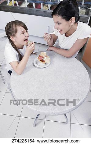 Girl and a teenage girl eating ice cream in an ice cream parlor View Large Photo Image Picture - Girl and a teenage girl eating ice cream in an ice cream parlor. Fotosearch