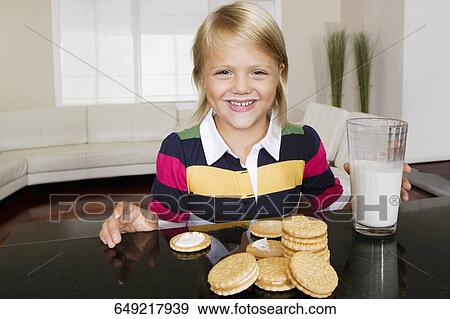 Girl having cookies and milk View Large Photo Image Stock Photo - Girl having cookies and milk. Fotosearch