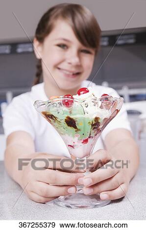 Stock Photo - Girl holding a glass of ice cream and smiling. Fotosearch