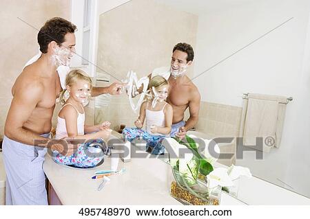 Stock Image - Girl playing with her father in the bathroom. Fotosearch