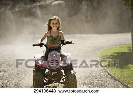 Stock Photo - Girl riding a quadbike and smiling. Fotosearch