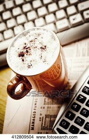 High angle view of a coffee cup with a newspaper and a calculator View Large Photo Image Picture - High angle view of a coffee cup with a newspaper and a calculator. Fotosearch