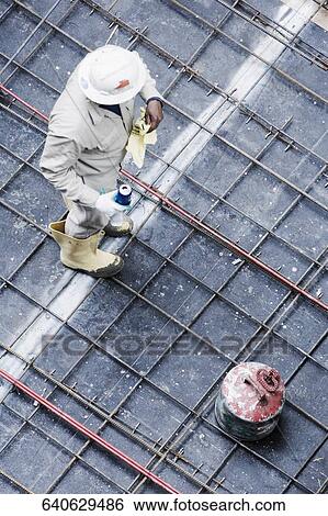 Stock Photograph - High angle view of a construction worker standing at a construction site. Fotosearch