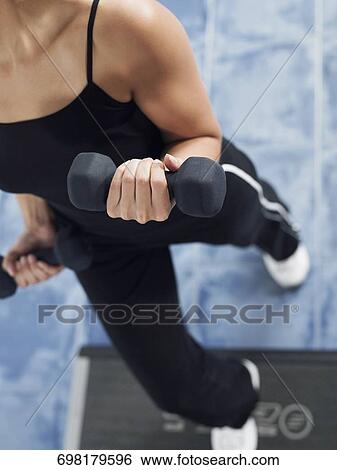High angle view of a mid adult woman exercising with dumbbells View Large Photo Image Stock Photograph - High angle view of a mid adult woman exercising with dumbbells. Fotosearch