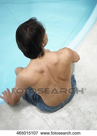 High angle view of a young man sitting at the poolside View Large Photo Image Stock Photo - High angle view of a young man sitting at the poolside. Fotosearch