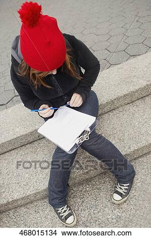 High angle view of a young woman sitting on steps and reading papers View Large Photo Image Picture - High angle view of a young woman sitting on steps and reading papers. Fotosearch