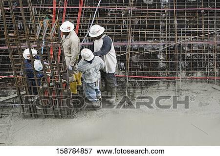 Stock Photo - High angle view of four construction workers working at a construction site. Fotosearch