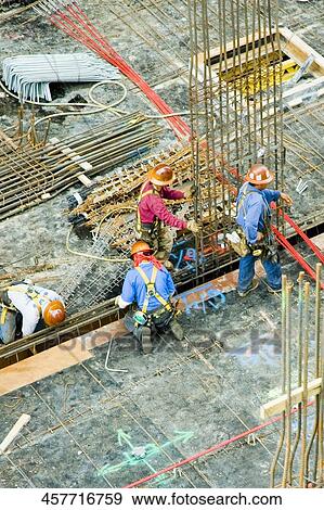 Stock Photo - High angle view of four construction workers working at a construction site. Fotosearch