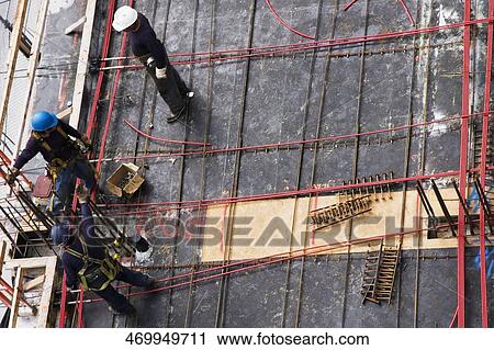 Stock Image - High angle view of three construction workers working at a construction site. Fotosearch