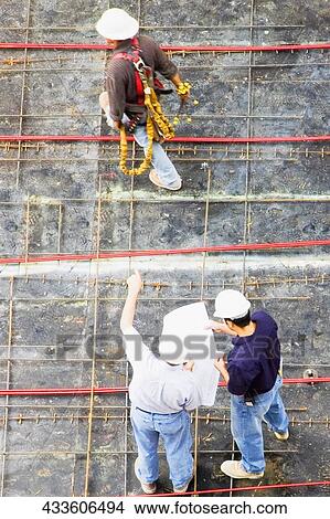 High angle view of two architects standing with a construction worker at a construction site View Large Photo Image Picture - High angle view of two architects standing with a construction worker at a construction site. Fotosearch