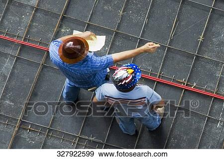 Stock Photo - High angle view of two architects standing at a construction site. Fotosearch