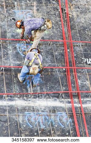 Stock Photo - High angle view of two construction workers working at a construction site. Fotosearch