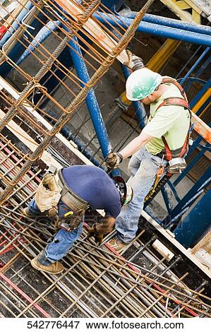 Stock Photo - High angle view of two construction workers working at a construction site. Fotosearch