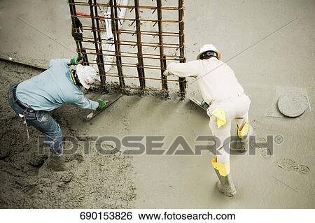 Stock Photograph - High angle view of two construction workers working at a construction site. Fotosearch