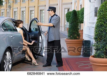 Stock Image - Hotel porter opening car door for a woman, Biltmore Hotel, Coral Gables, Florida, USA. Fotosearch