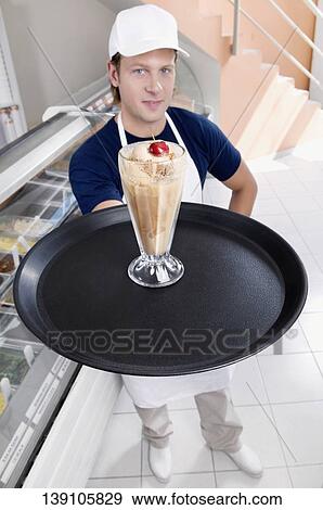 Ice cream seller holding a tray with a glass of ice cream View Large Photo Image Stock Photo - Ice cream seller holding a tray with a glass of ice cream. Fotosearch