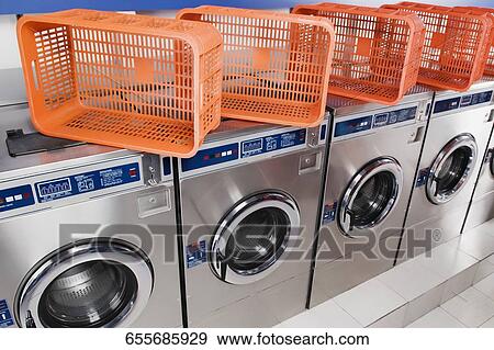 Stock Photo - Laundry baskets on washing machines in a laundromat. Fotosearch